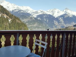 A balcony with a view of snow-capped mountains, a table, and a chair. - Studio for 4, station and Vanoise view (Valfréjus)