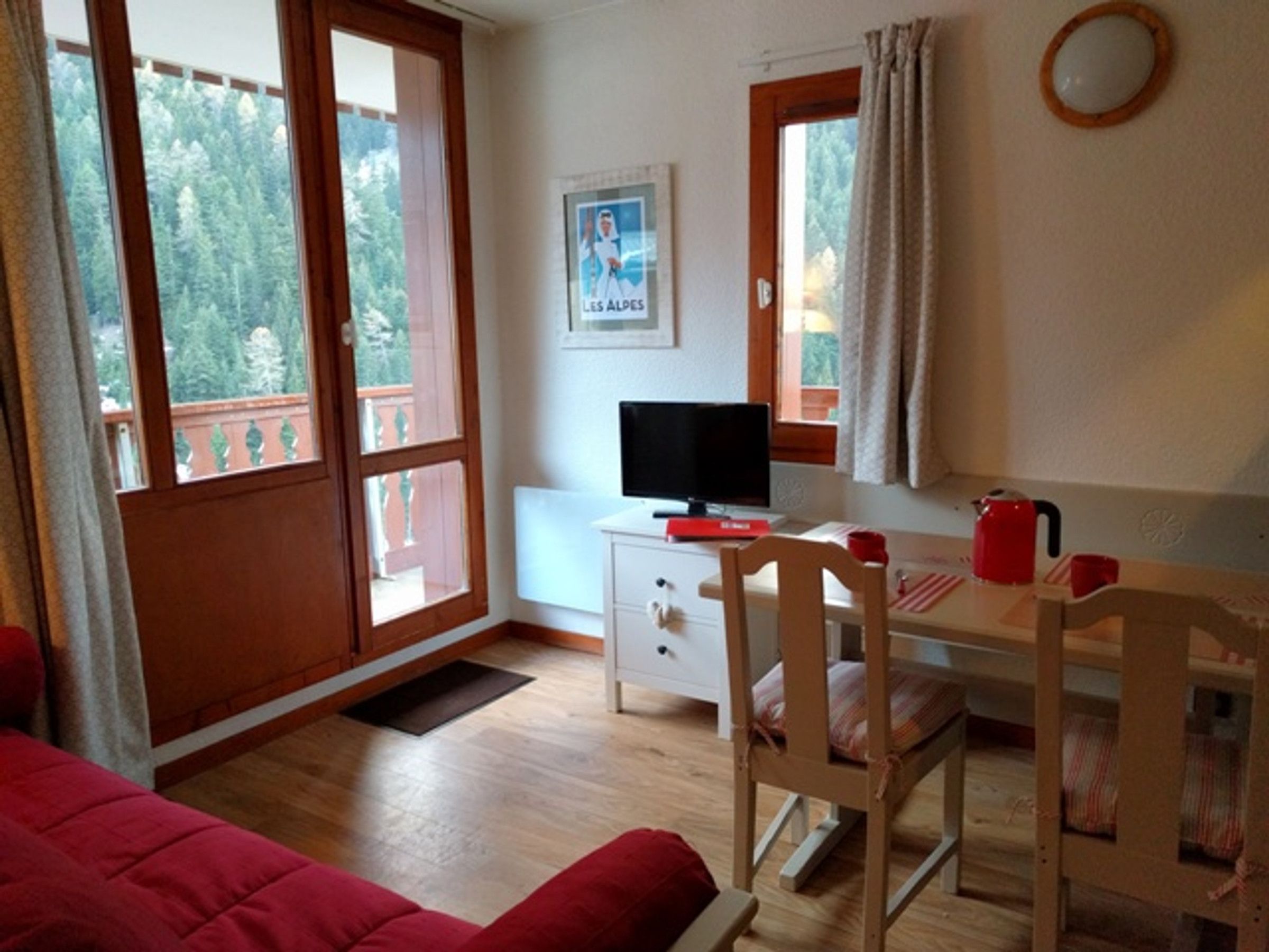 Une pièce comprenant un lit, un bureau avec un ordinateur, une chaise, une fenêtre avec des rideaux et une affiche accrochée au mur.
