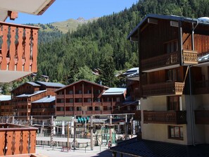 A wooden building with balconies, a playground, and a mountainous backdrop. - Studio for 4, station and Vanoise view (Valfréjus)
