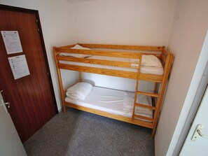 Ein Stockbett mit Holzbettgestell, eine Tür mit einem Hinweisschild und ein Teppichboden.