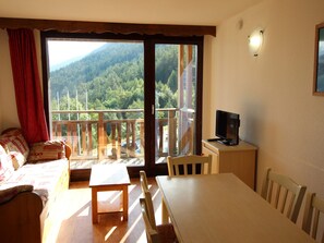 Une chambre avec un balcon, un lit, une table et un téléviseur.