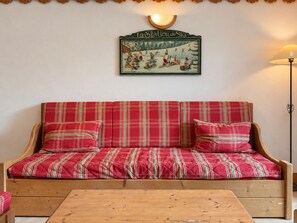 A wooden sofa with red and green plaid upholstery, a wall-mounted sign with a ski scene, and a floor lamp. - Comfortable apartment - 6 guests (Champagny-en-Vanoise)