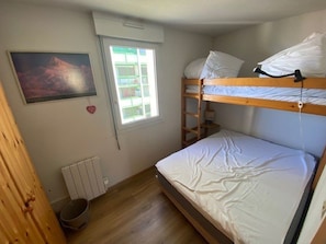 A bunk bed room with a window, a radiator, and a painting on the wall. - Practical apartment, slopes view - 5 guests (Arette)