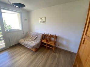 A room with a bed, a wooden chair, a radiator, a window, and a wall-mounted picture. - Practical apartment, slopes view - 5 guests (Arette)
