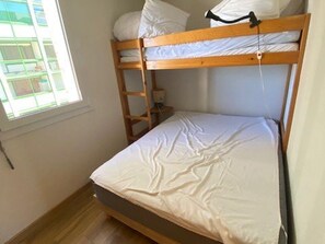 A bunk bed with a ladder, a window with blinds, and a wooden floor. - Practical apartment, slopes view - 5 guests (Arette)