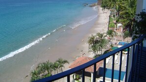 A beach view from a balcony with a pool and palm trees. - Loaded 2-bedroom view condo on the prettiest
beach in Vallarta (Jal.)
