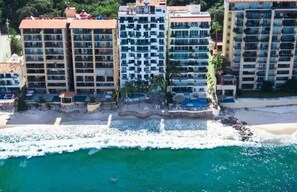 A beachfront hotel with multiple floors, balconies, and a pool area. - Loaded 2-bedroom view condo on the prettiest 
beach in Vallarta (Jal.)