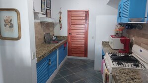 A compact kitchen with a red door, blue cabinets, a gas stove, and a microwave. - Loaded 2-bedroom view condo on the prettiest
beach in Vallarta (Jal.)