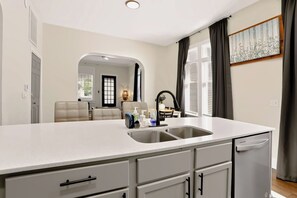 A modern kitchen with a large island, double sink, and integrated dishwasher. - Spacious 2BR Near Downtown Indy | Sleeps 6 (Indianapolis)