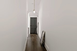 A narrow hallway with a dark wooden floor, white walls, and a door at the end. - Spacious 2BR Near Downtown Indy | Sleeps 6 (Indianapolis)