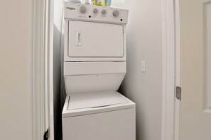 Una lavadora y secadora Whirlpool blancas y compactas en un lavadero pequeño y cerrado con una puerta a un lado.