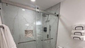 Een badkamer met een glazen douchecabine, toilet, wastafel en handdoekhouder.
