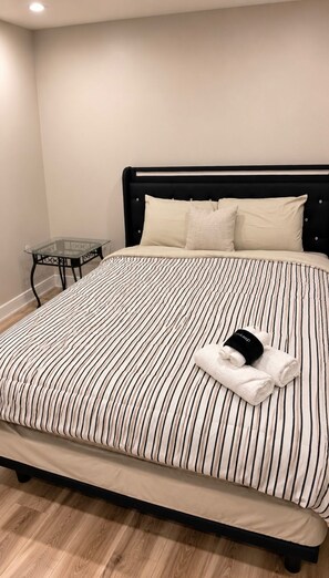 A bed with a striped bedspread, a black headboard, and a glass side table with a black frame. - Entire home in Aldie, Virginia, United States (Aldie)