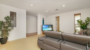 Un salon moderne avec un canapé en cuir, un téléviseur à écran plat et une plante en pot.