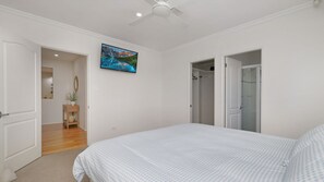 A bedroom with a bed, a ceiling fan, a painting, and a bathroom door. - Salt Gardens – Private Pool & Tea Gardens Retreat (Tea Gardens)