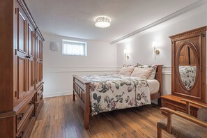 Una camera da letto con un letto in legno, un comodino, una cassettiera, uno specchio e una lampada a soffitto.