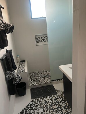 A bathroom with a checkered floor, a towel rack with towels, a small window, and a sink. - The Chesterfield House: Luxury Caribbean Escape in Barbados (St. Michael, M10)