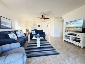 A living room with a sofa, armchairs, a coffee table, and a television on a cabinet. - 2BR Riverhouse Condo – Pools, Golf & Beaches (Rotonda West)