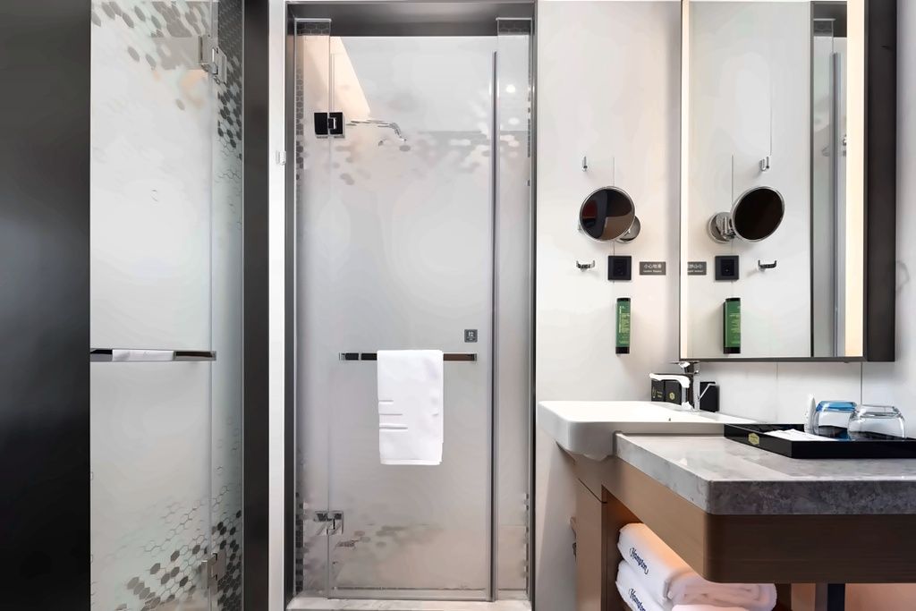 A modern bathroom with a glass-enclosed shower, a sink with a mirror, and a towel rack.