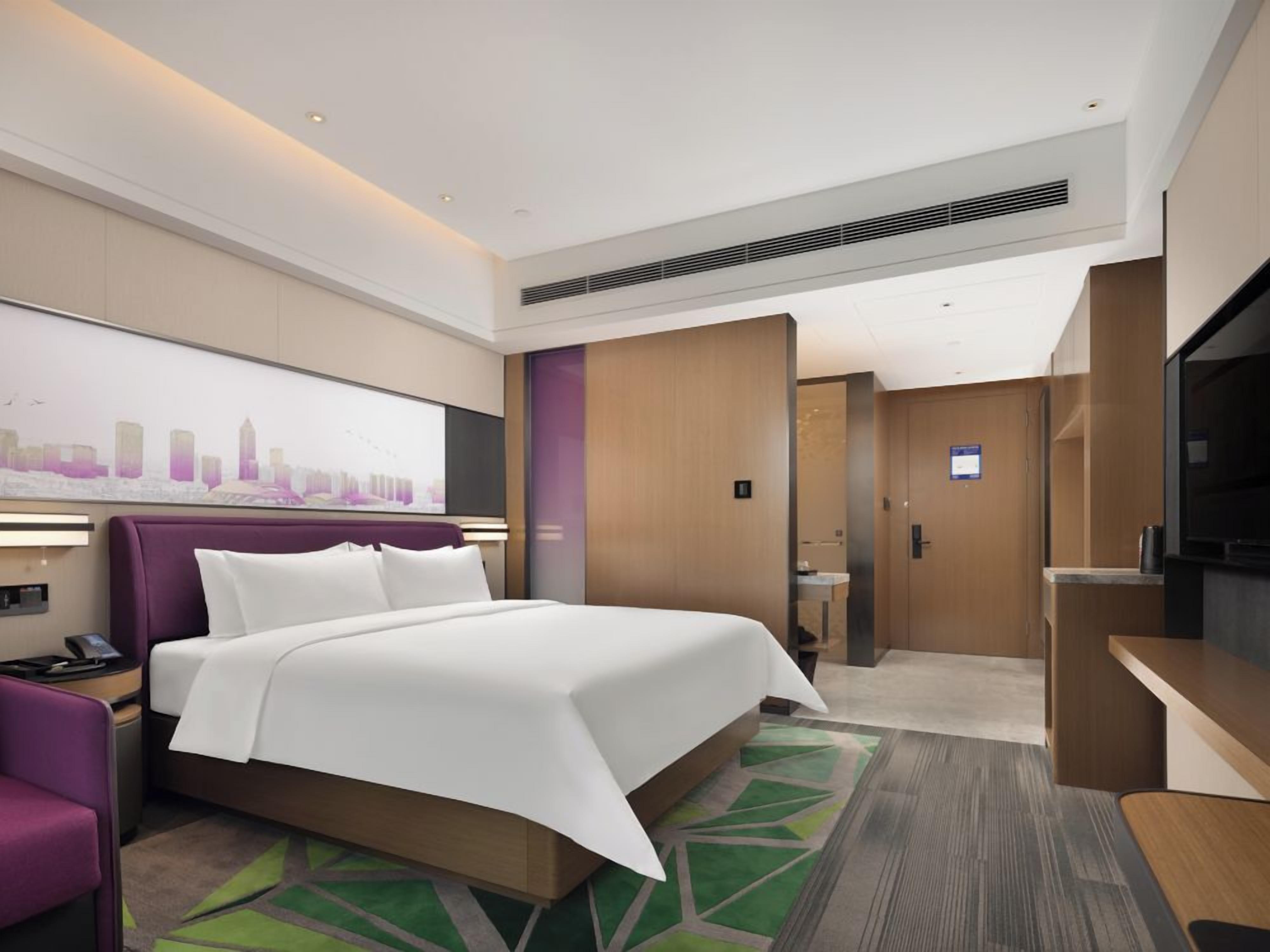 A hotel room with a large bed, a desk, a television, and a bathroom.
