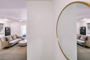 Uma sala de estar moderna com um sofá, mesa de centro e um espelho grande.