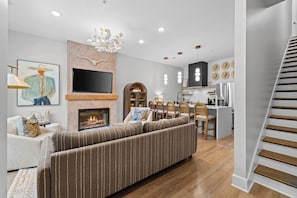 A modern living room with a fireplace, a television, and a dining area with wooden chairs. - Stunning Home on Music Row - Rooftop TV, Sauna, & Grill Near Broadway! (Nashville)