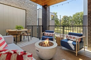 A covered outdoor seating area with a fire pit, wicker furniture, and a view of the surrounding landscape. - Stunning Home on Music Row - Rooftop TV, Sauna, & Grill Near Broadway! (Nashville)