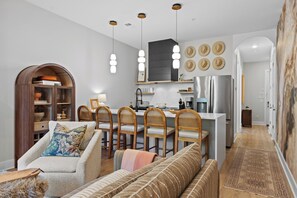 A modern kitchen with a central island, wooden chairs, and a dining table. - Stunning Home on Music Row - Rooftop TV, Sauna, & Grill Near Broadway! (Nashville)