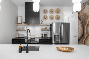 Een moderne keuken met een roestvrijstalen koelkast, een koffiezetapparaat en een gasfornuis.
