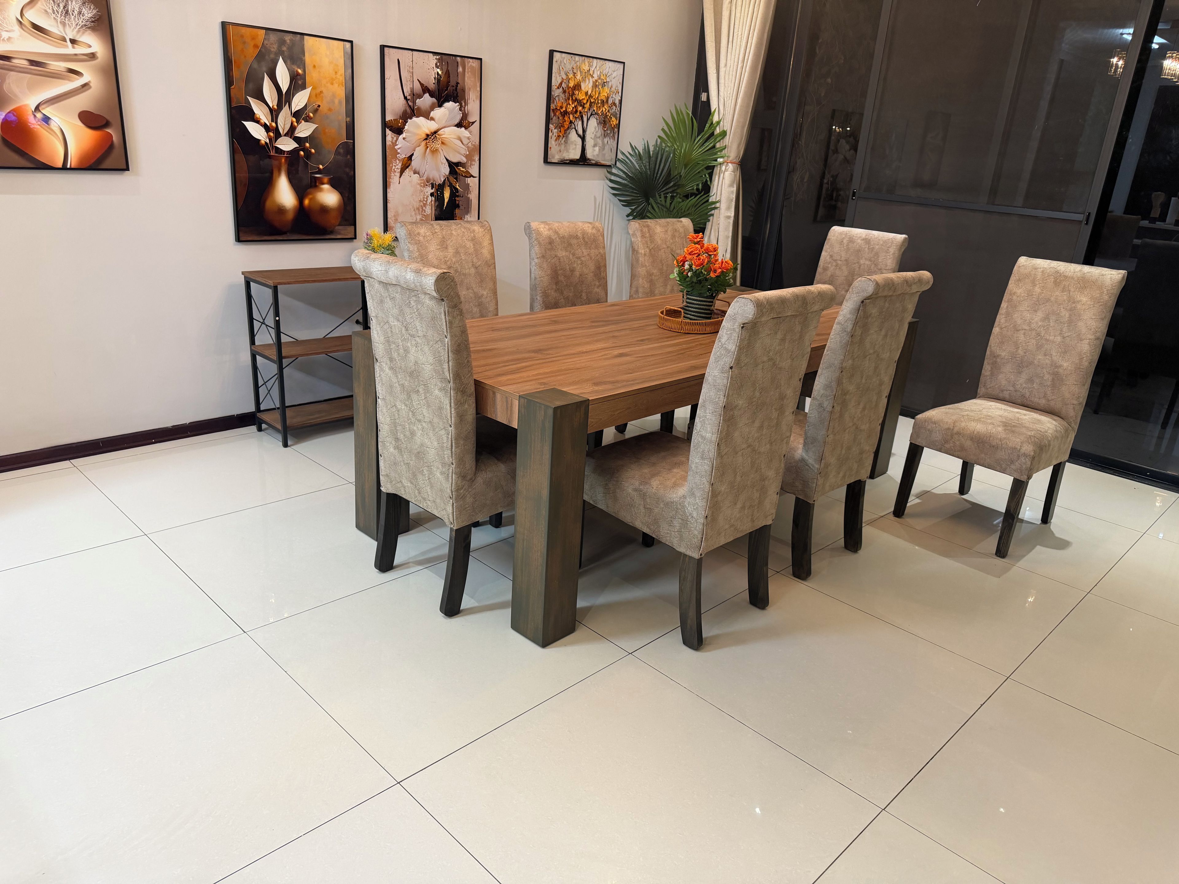 Un coin repas avec une table en bois et six chaises rembourrées, le tout agrémenté d’œuvres d’art accrochées aux murs.