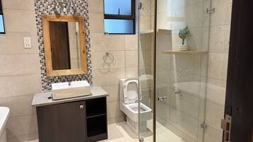 Un bagno moderno con doccia vetrata, mobile bagno in legno con lavabo e servizi igienici.