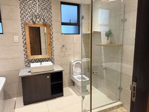 Un bagno moderno con doccia vetrata, mobile bagno in legno con lavabo e servizi igienici.