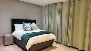 A modern bedroom with a bed, nightstand, and curtains.