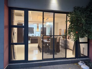 Un interno moderno con zona pranzo, cucina e un'ampia porta-finestra scorrevole che si apre su un balcone.