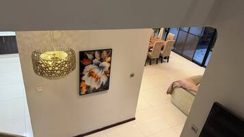 Um interior moderno com uma escada, uma área de refeições com cadeiras e uma obra de arte suspensa na parede.