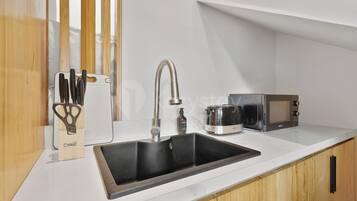 A modern kitchen with a black sink, stainless steel appliances, and wooden cabinetry.