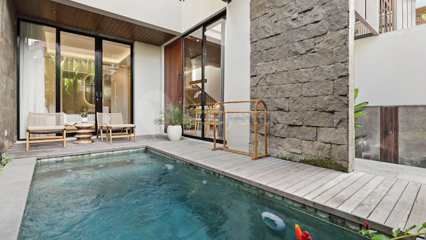 Uma área moderna de piscina ao ar livre, com deck de madeira, parede de pedra e porta de vidro que dá para uma área de estar.