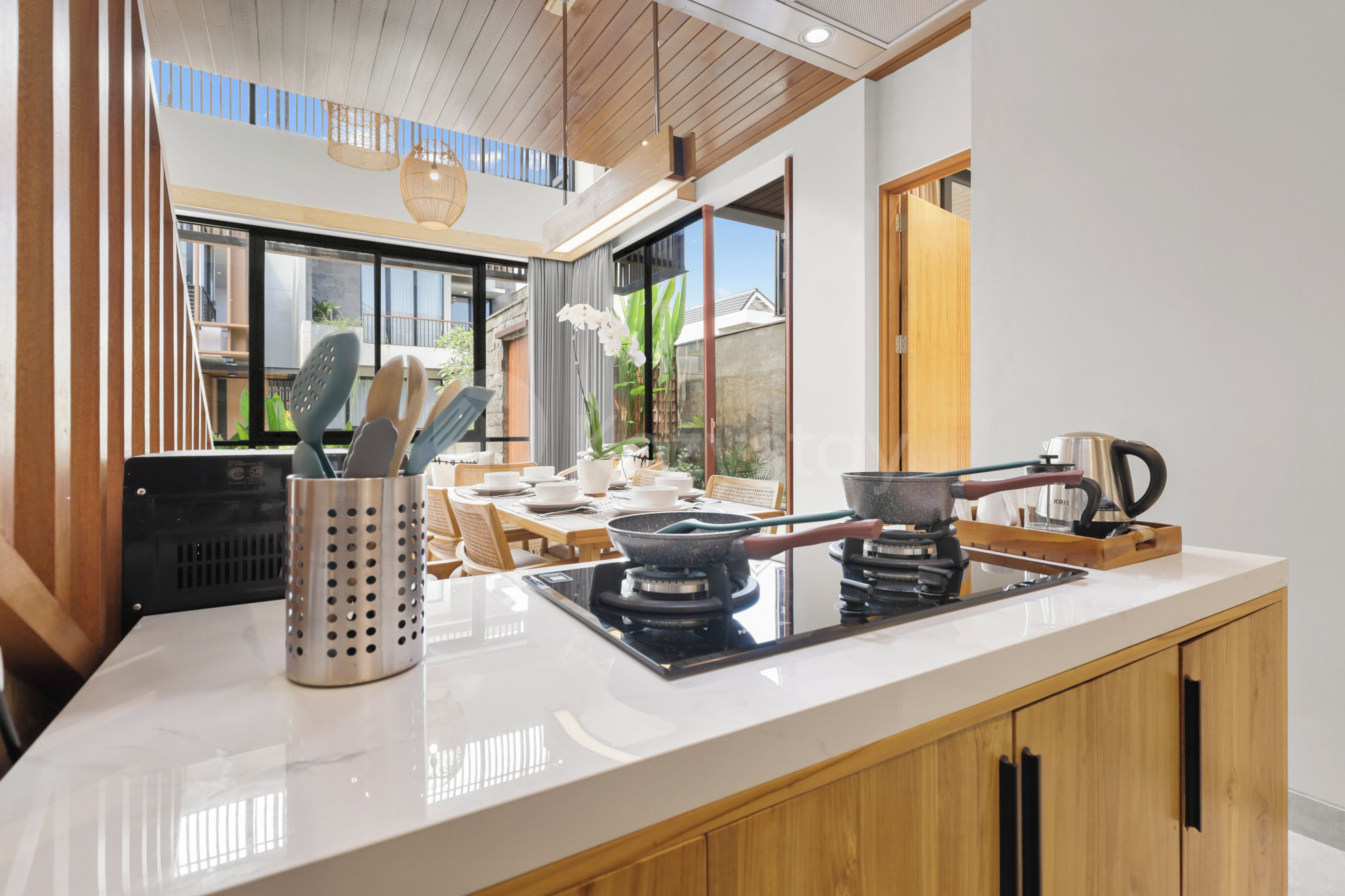 A modern kitchen with a central island, stainless steel appliances, and a view of the outdoors.