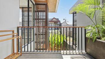 Un balcón moderno con piso de madera, barandilla de metal y vista a una zona residencial.