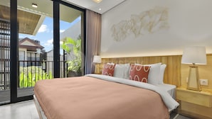 Quarto de hotel com uma cama grande, porta de vidro deslizante para uma varanda e luminária fixada na parede.