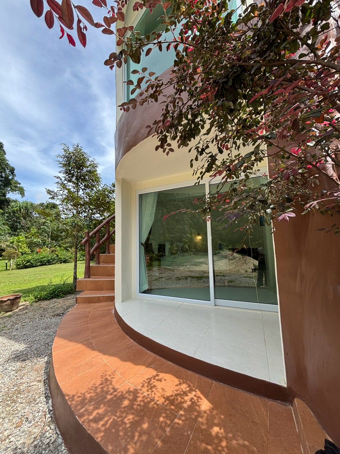 A modern building with a curved exterior, large glass windows, and a stone pathway leading to the entrance.