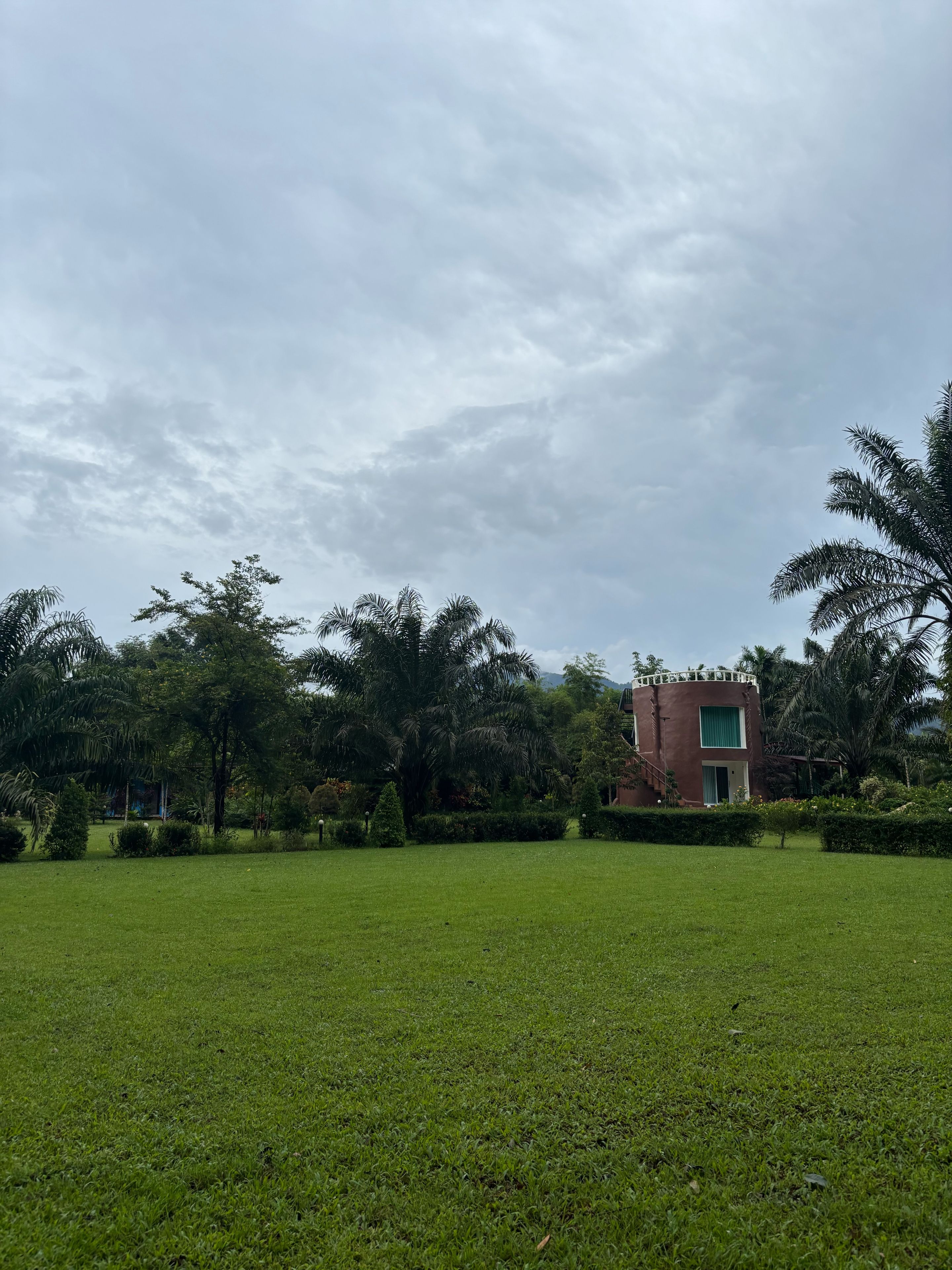 A grassy area with a building featuring a red facade and a window.