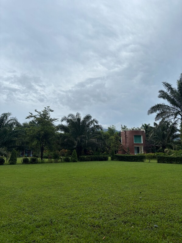 A grassy area with a building featuring a red facade and a window. - khaosoksaengtawanresortandcamp (Phanom)