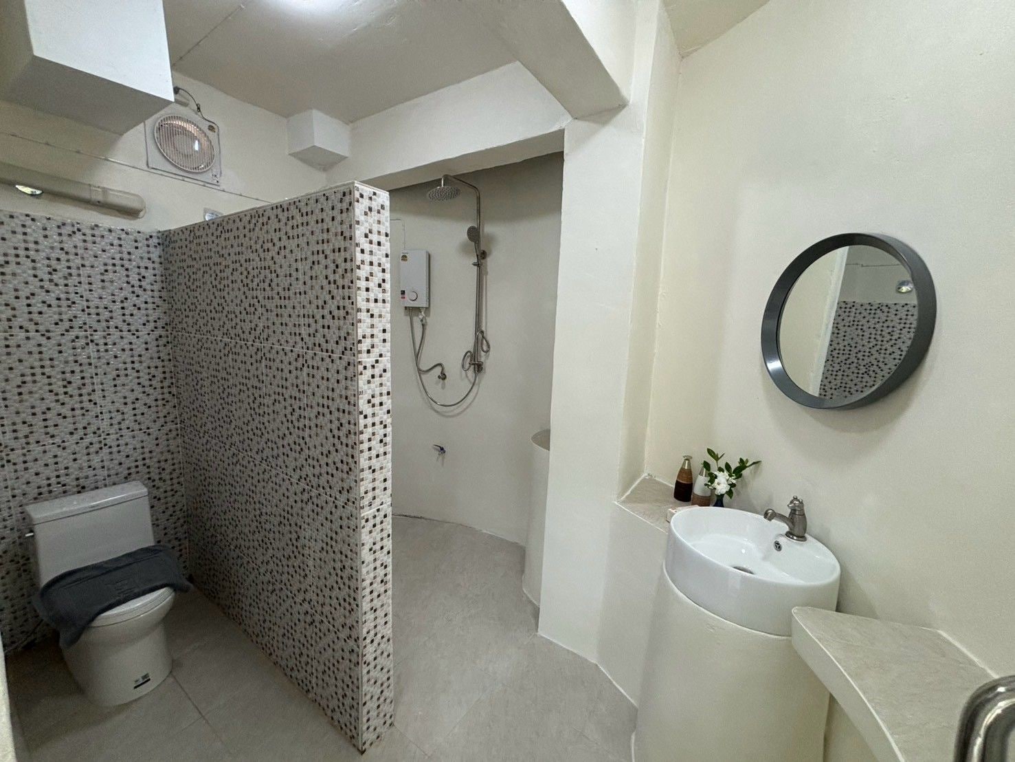 Une salle de bain équipée de toilettes, d’une douche, d’un lavabo et d’un miroir.