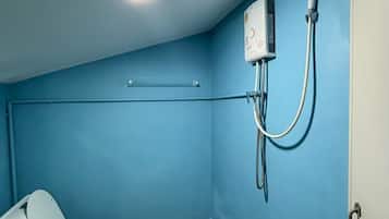 Un baño pequeño y cerrado con inodoro, cabina de ducha y calentador de pared.