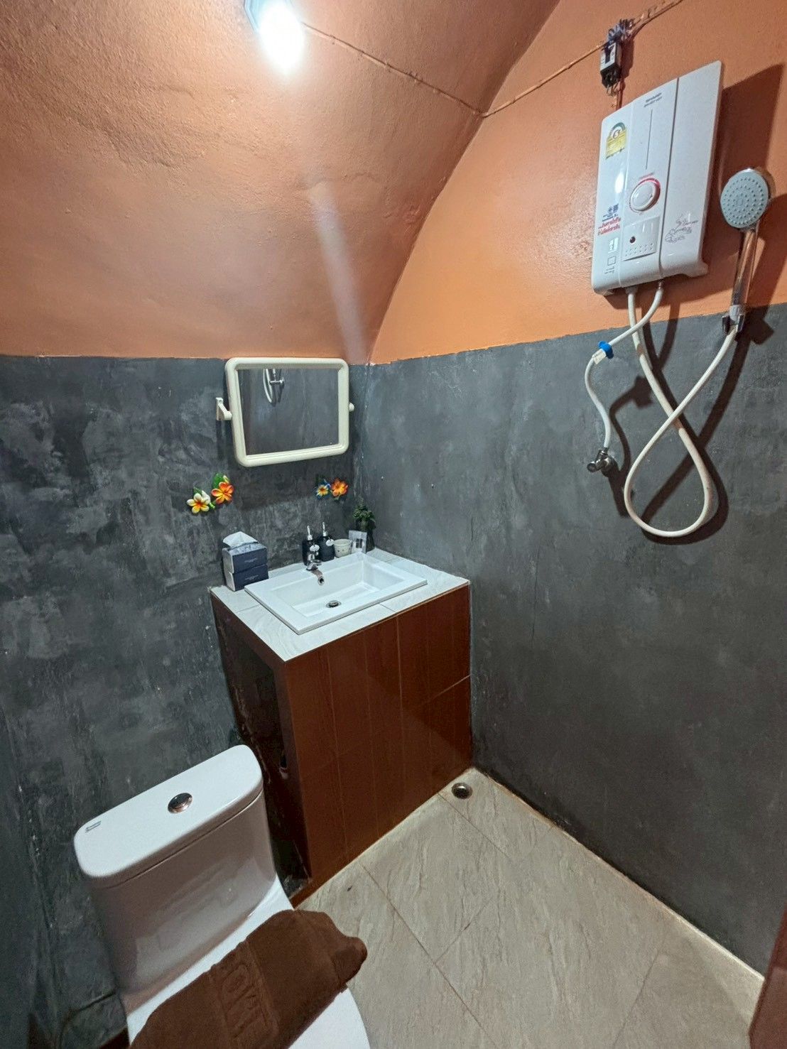 A small bathroom with a toilet, sink, and shower unit.