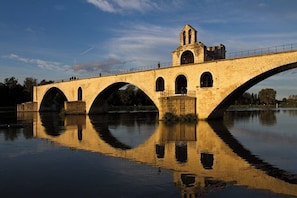Eine Steinbrücke mit mehreren Bögen, die sich im darunterliegenden Gewässer spiegelt.