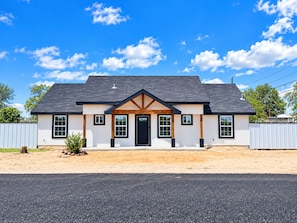 A two-story house with a dark roof, white walls, and a front porch.
