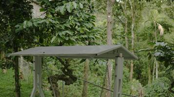 A swing set in a garden with a metal frame, wooden seat, and chains.