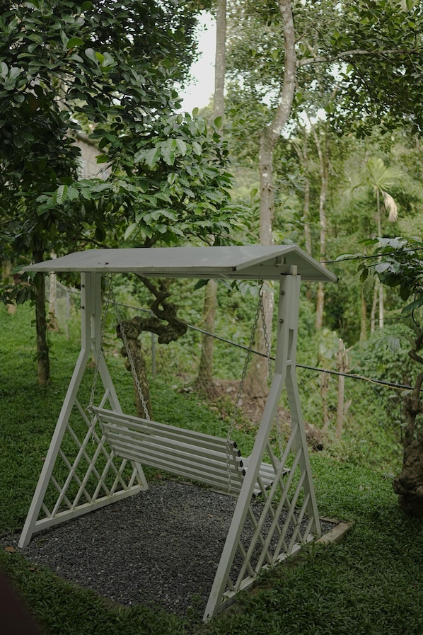 A swing set in a garden with a metal frame, wooden seat, and chains.
